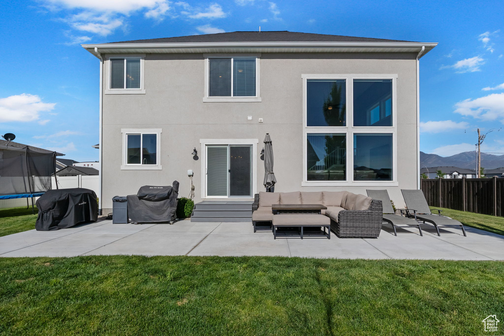 Rear view of property with a trampoline, a patio, stucco siding, and an outdoor hangout area