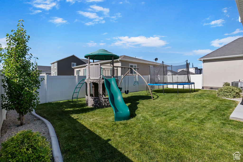 Communal playground featuring a trampoline and a fenced backyard