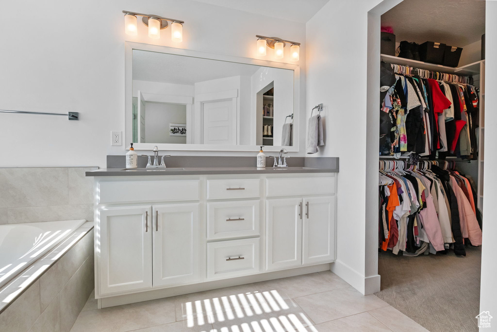 Full bath with double vanity, tile patterned flooring, a bath, and a walk in closet