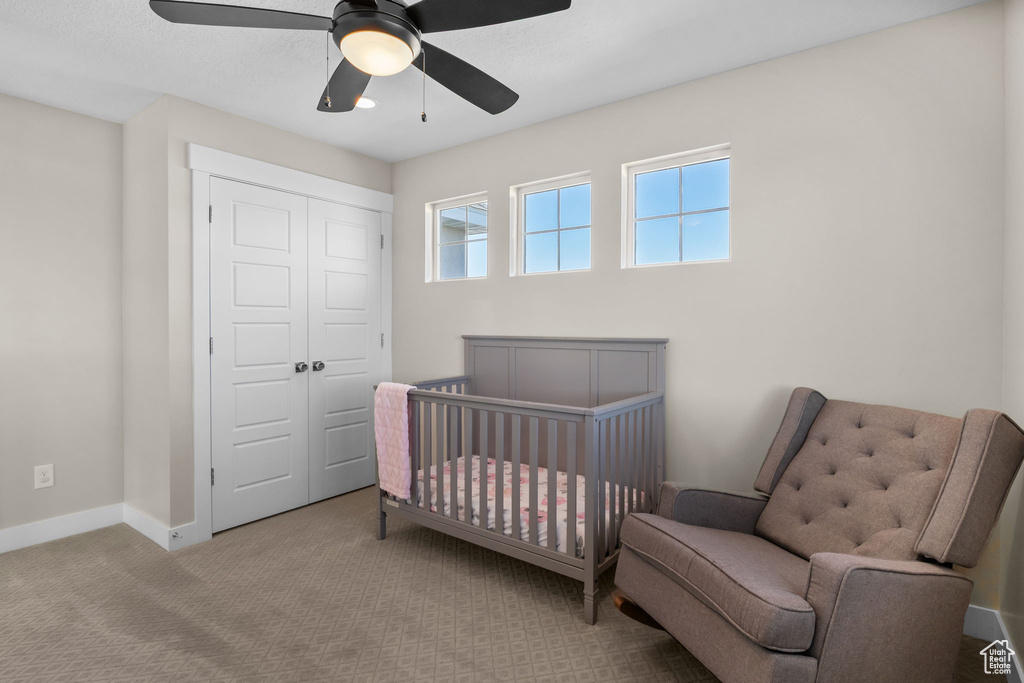 Bedroom with a closet, carpet floors, ceiling fan, and a nursery area