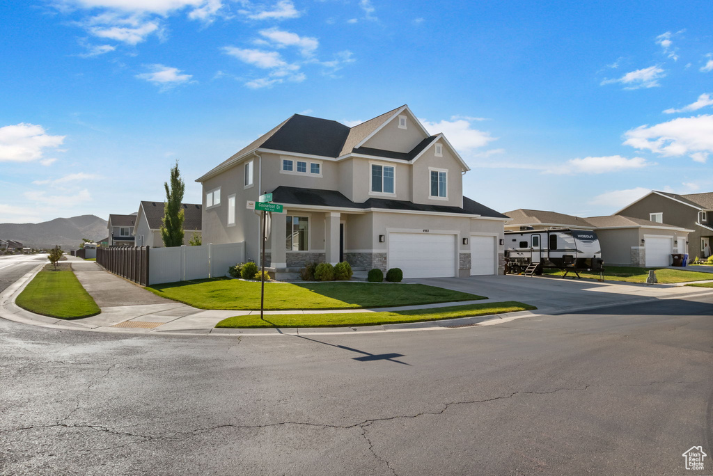 View of front of home featuring stone siding, an attached garage, a residential view, stucco siding, and driveway
