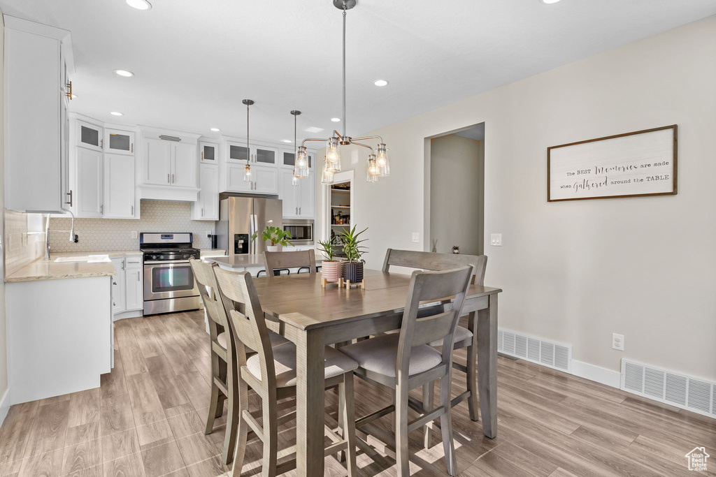 Dining room with recessed lighting, a chandelier, and light wood-style flooring