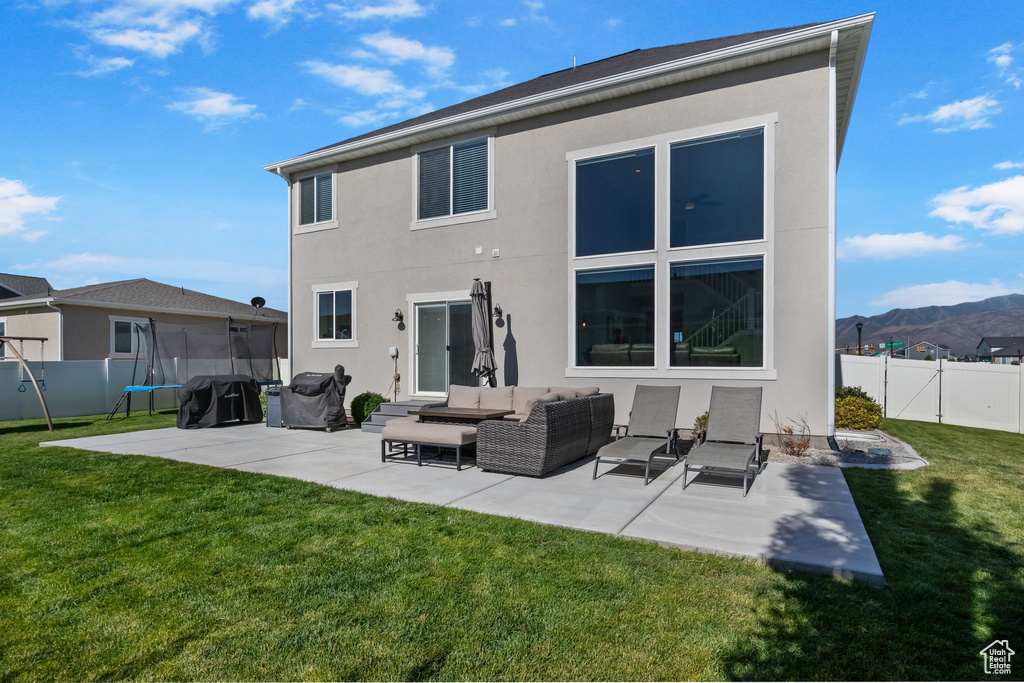Rear view of house featuring a patio area, stucco siding, a fenced backyard, and a trampoline
