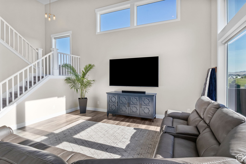 Living area with stairs, wood finished floors, and a high ceiling