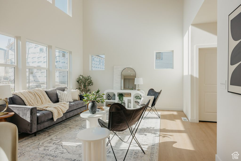 Living area featuring a towering ceiling and light wood-style flooring