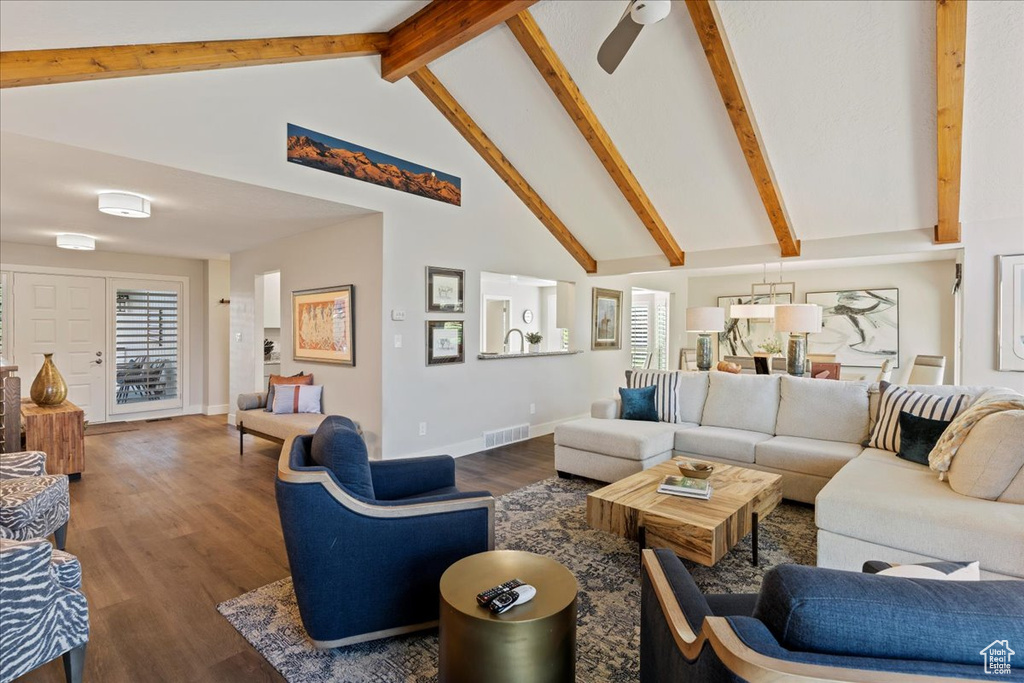 Living area with high vaulted ceiling, wood finished floors, beam ceiling, and a ceiling fan