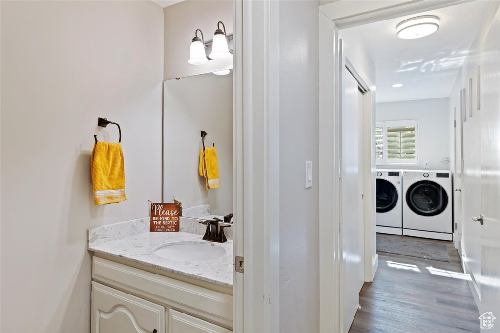 Bathroom with washing machine and clothes dryer, vanity, and wood finished floors