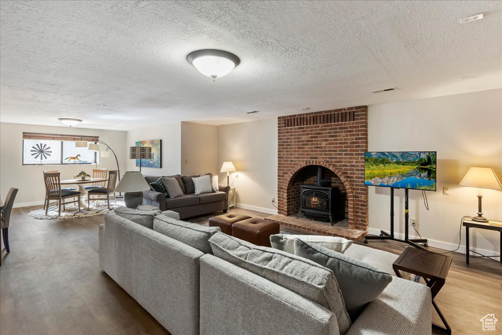 Living area featuring a wood stove, a textured ceiling, and wood finished floors