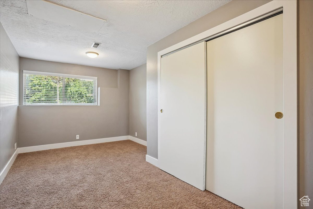 Unfurnished bedroom featuring carpet, a textured ceiling, and a closet