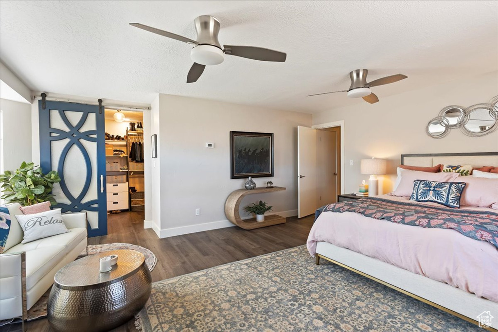Bedroom featuring wood finished floors, a spacious closet, ceiling fan, and a textured ceiling