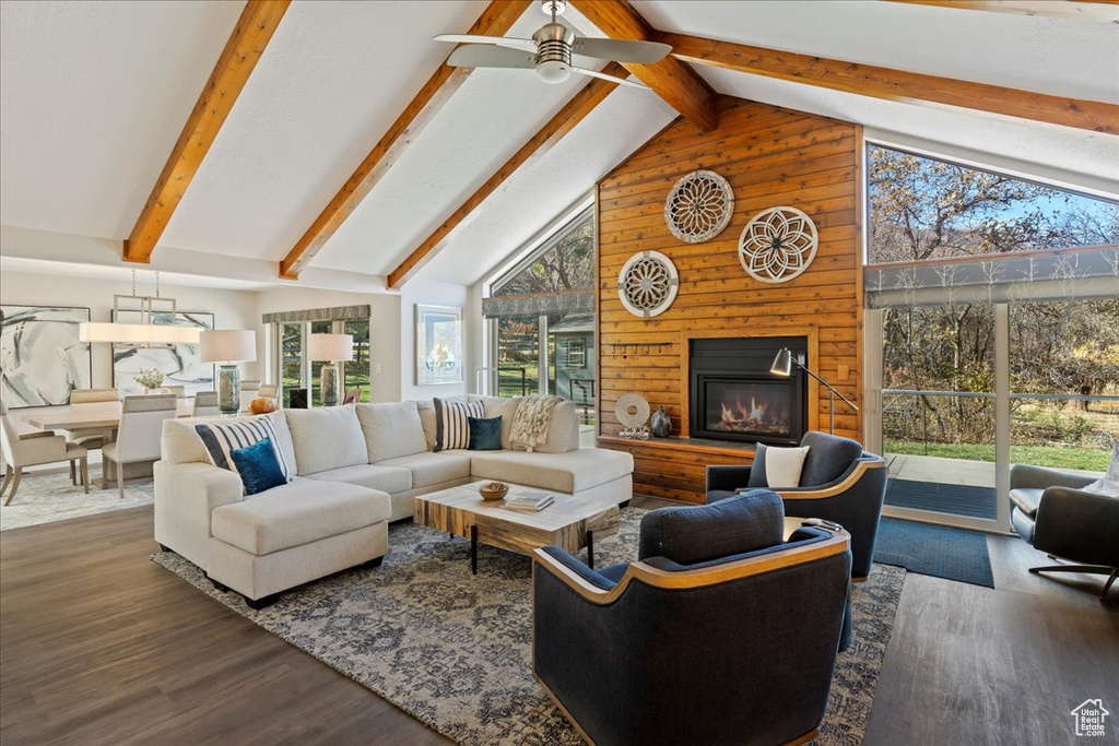 Living area with healthy amount of natural light, wood finished floors, high vaulted ceiling, wooden walls, and beamed ceiling