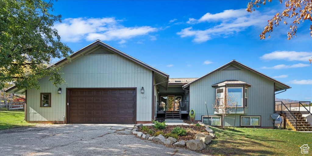 View of front of house featuring stairway, an attached garage, driveway, and a front yard