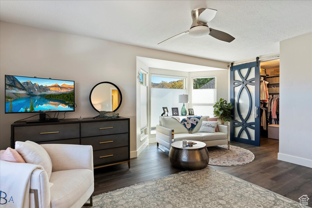 Living area featuring wood finished floors, a ceiling fan, and a textured ceiling