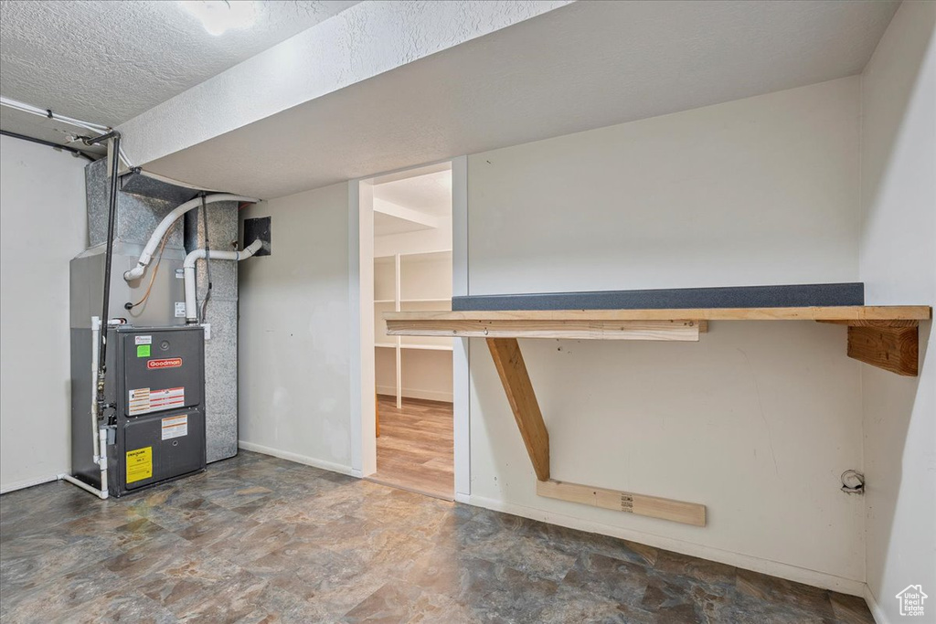 Finished basement featuring stone finish flooring, heating unit, and a textured ceiling