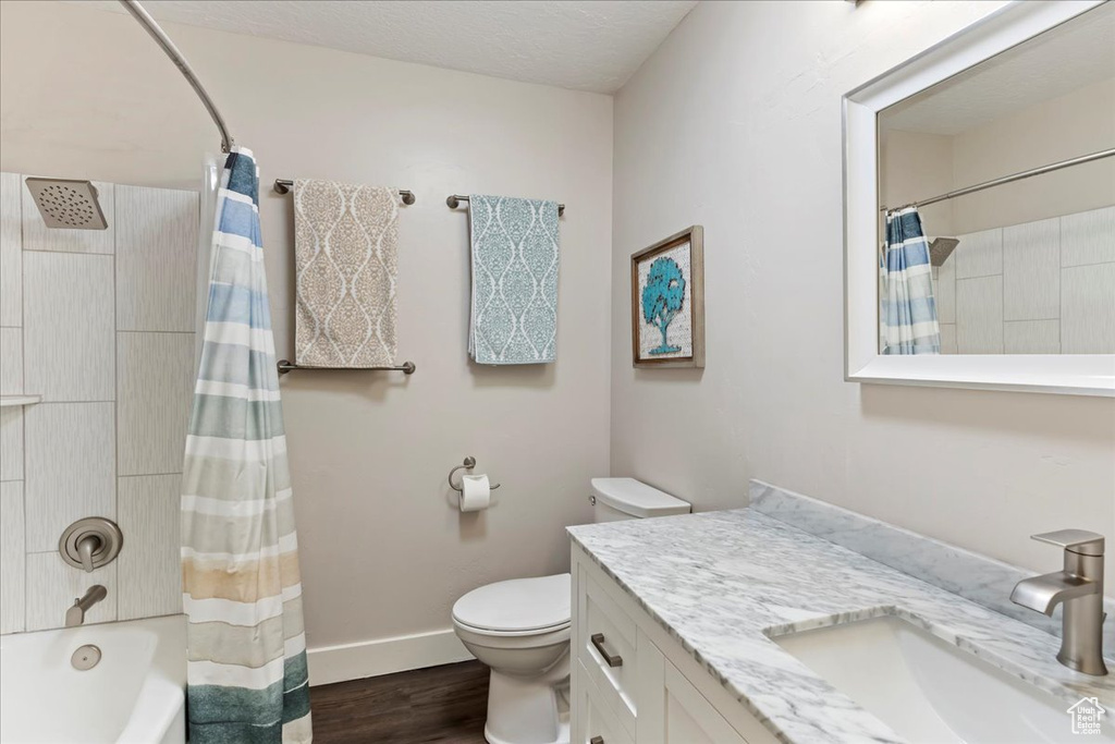 Full bathroom with vanity, wood finished floors, and shower / bathtub combination with curtain