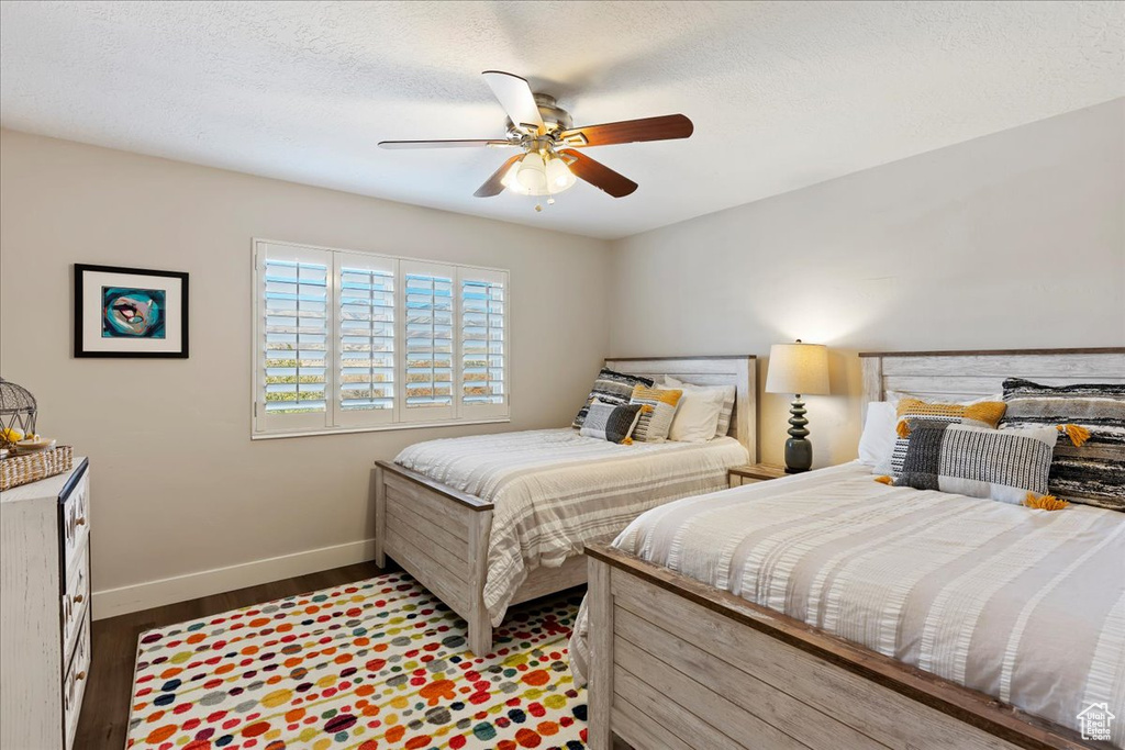 Bedroom with wood finished floors, ceiling fan, and a textured ceiling