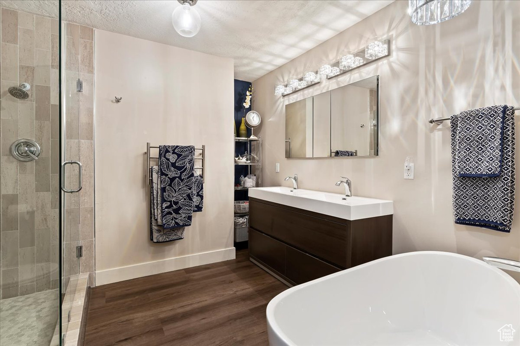 Bathroom with a soaking tub, a shower stall, wood finished floors, and double vanity