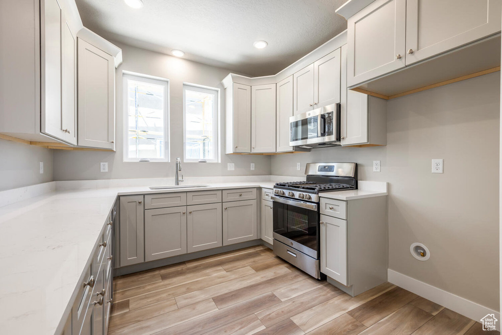 Kitchen featuring appliances with stainless steel finishes, light wood-style flooring, recessed lighting, and light stone counters
