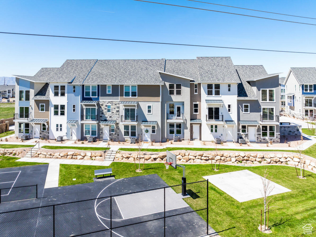 Rear view of property with stucco siding, community basketball court, a residential view, and a yard