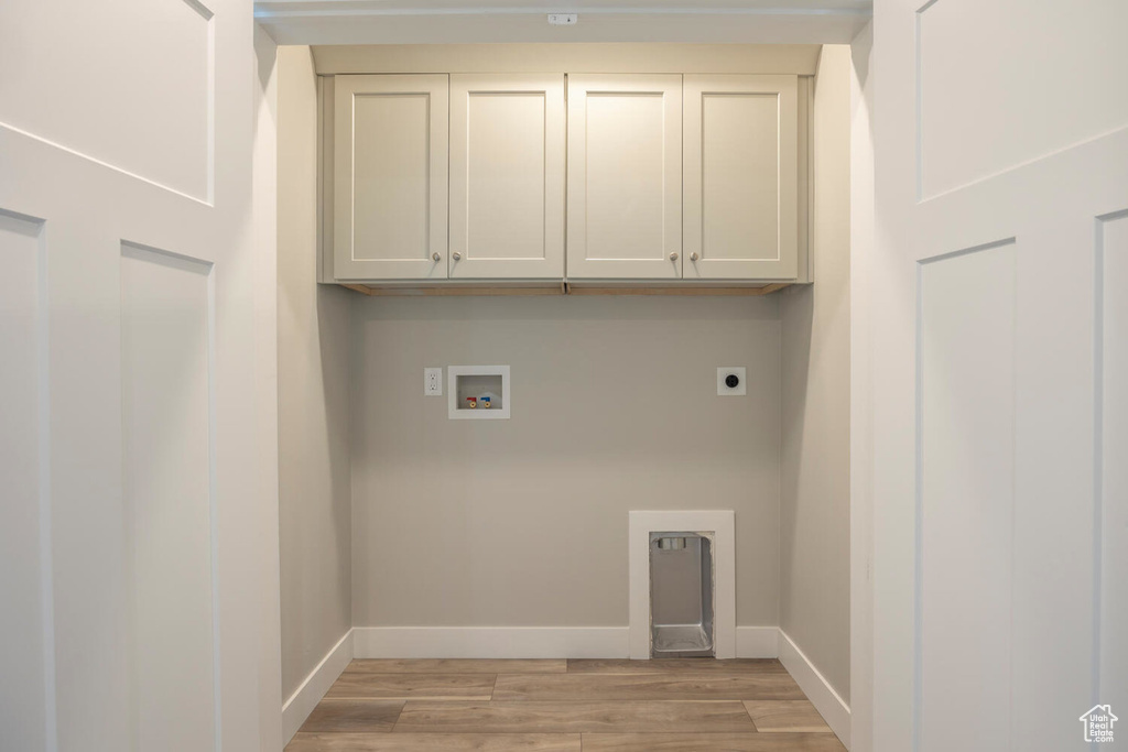 Laundry area with electric dryer hookup, light wood-type flooring, washer hookup, and cabinet space