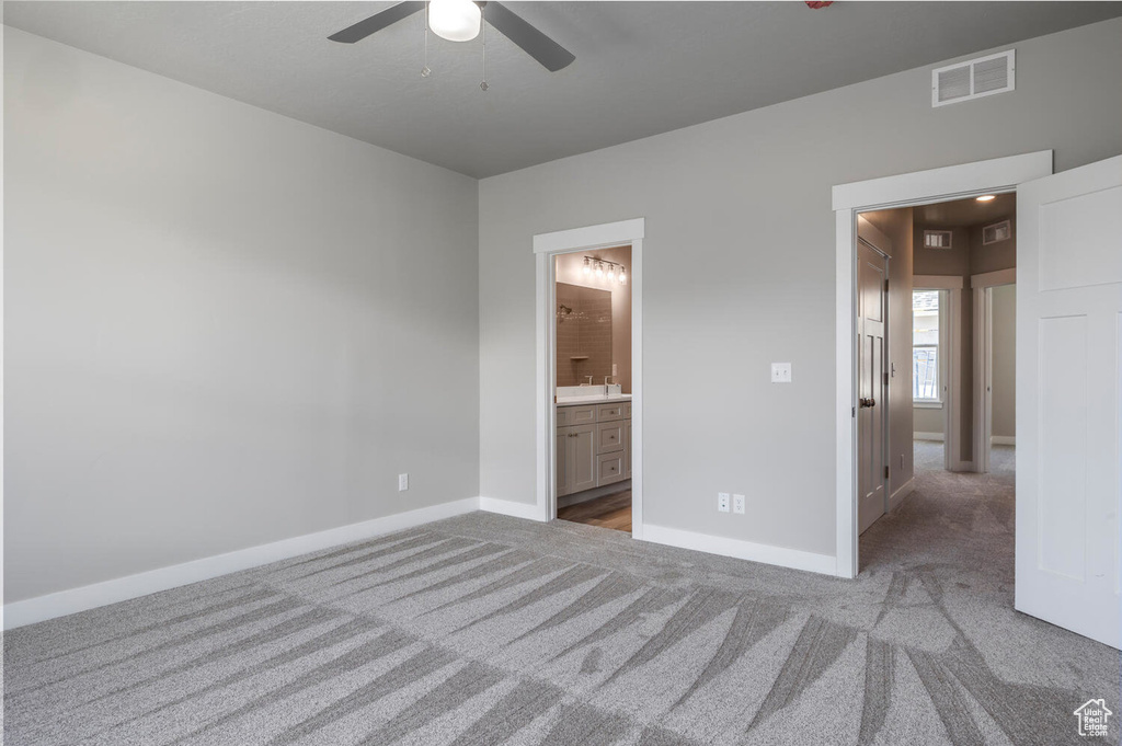 Unfurnished bedroom with carpet, connected bathroom, and ceiling fan