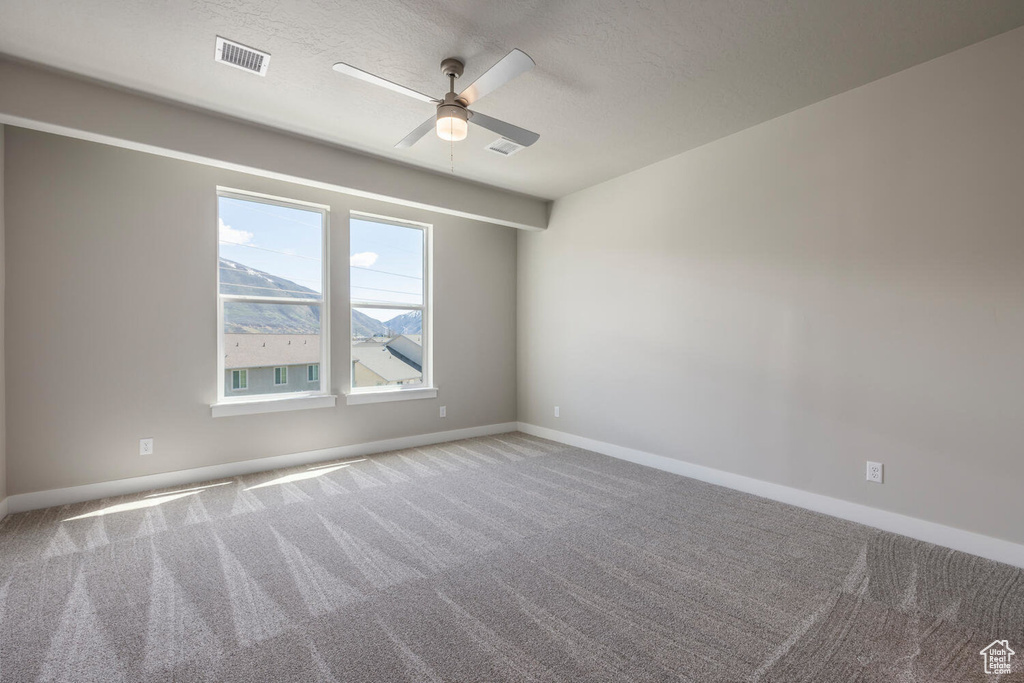 Empty room with a ceiling fan, carpet flooring, and a textured ceiling