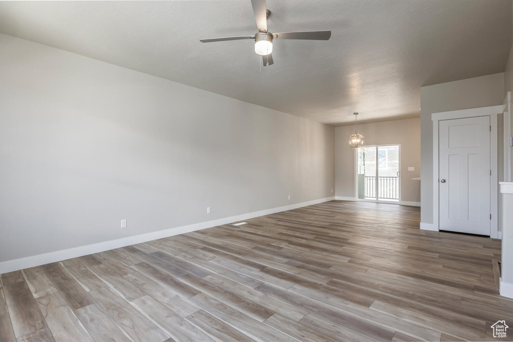 Spare room featuring a ceiling fan, wood finished floors, and a chandelier