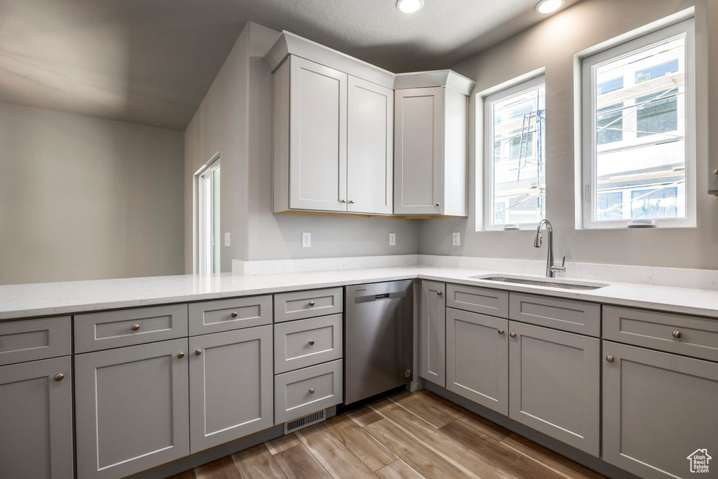 Kitchen with stainless steel dishwasher, gray cabinetry, light wood-style flooring, light stone counters, and recessed lighting