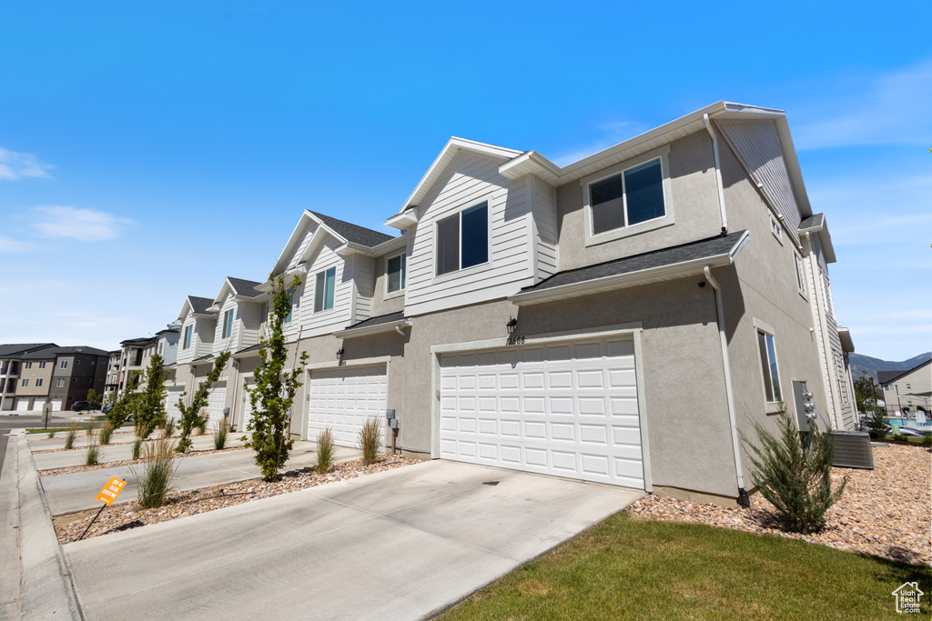 View of front of house featuring stucco siding, a residential view, driveway, and a garage