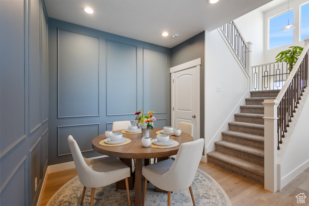 Dining space featuring a decorative wall, stairway, light wood-style flooring, and recessed lighting
