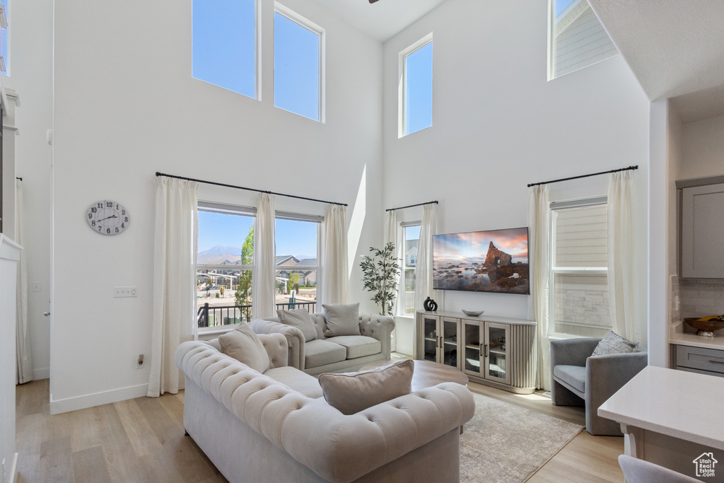 Living area with a towering ceiling, light wood-style flooring, and healthy amount of natural light