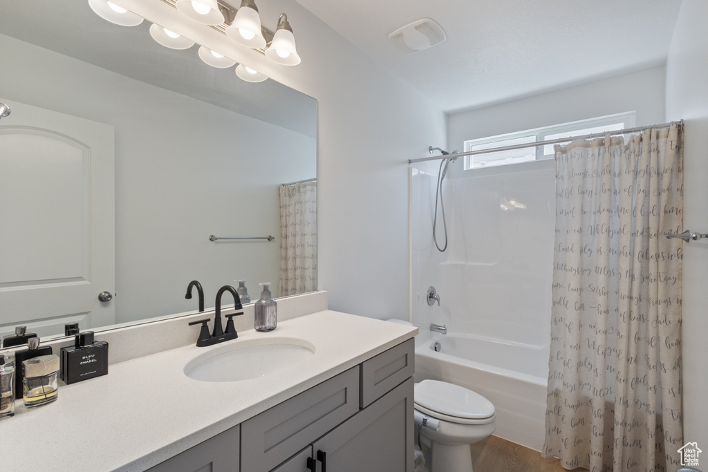Full bathroom featuring shower / bath combo, vanity, and wood finished floors