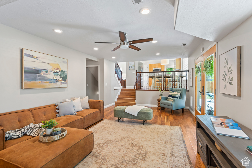Living area featuring wood finished floors, stairway, ceiling fan, and recessed lighting