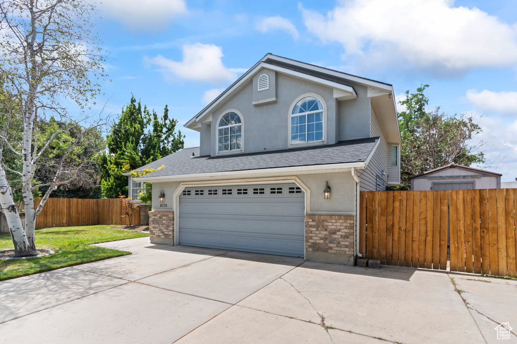 Traditional-style house with driveway, an attached garage, brick siding, stucco siding, and roof with shingles