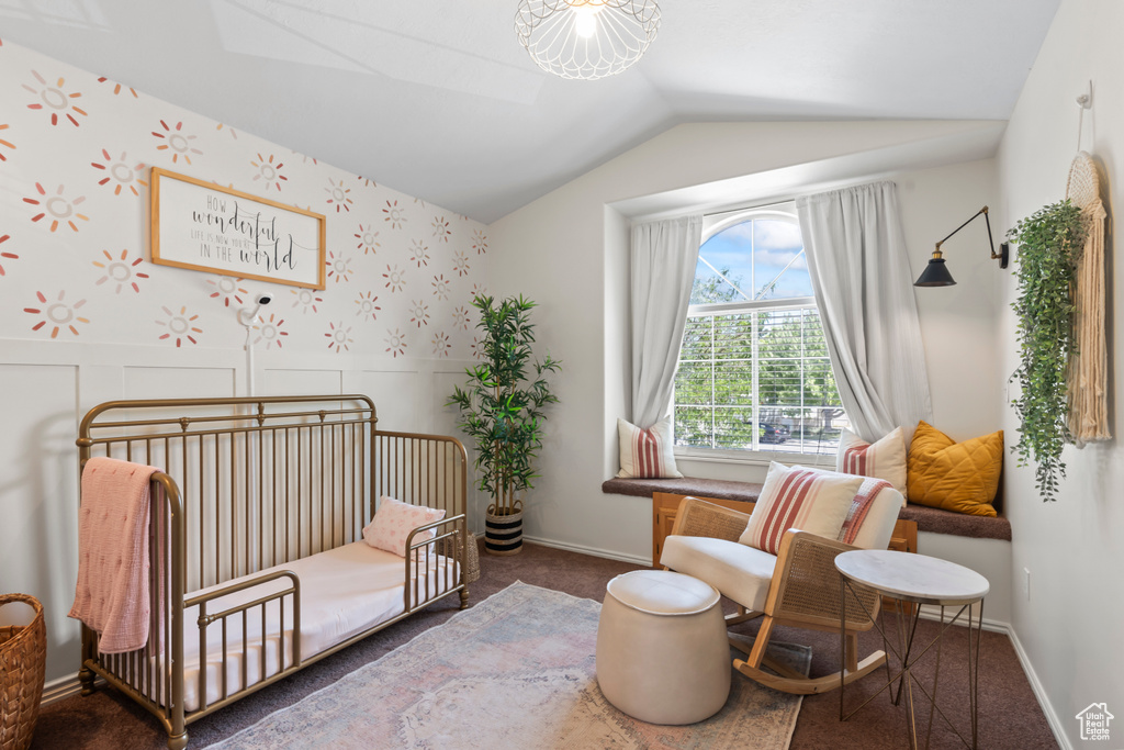 Bedroom with a nursery area, carpet floors, wainscoting, and lofted ceiling