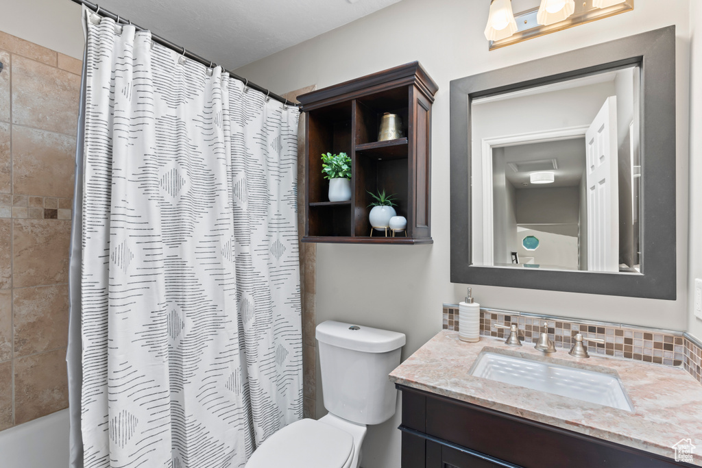 Bathroom featuring vanity, shower / bath combination with curtain, and tasteful backsplash