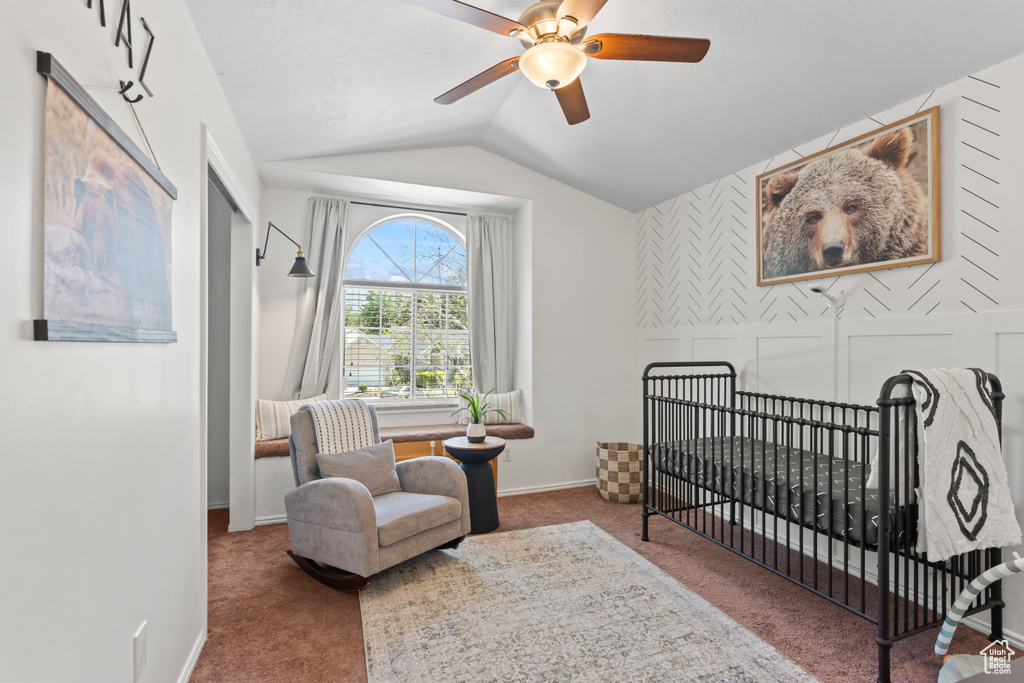 Bedroom featuring lofted ceiling, carpet, a nursery area, and a ceiling fan