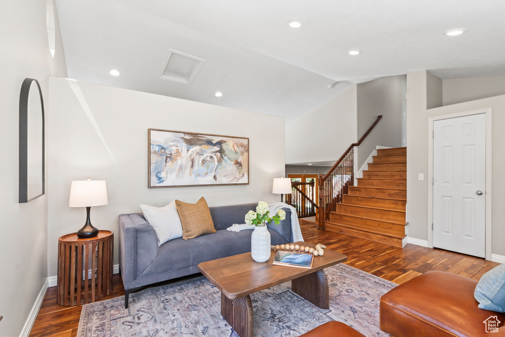 Living area with wood finished floors, lofted ceiling, recessed lighting, and stairs