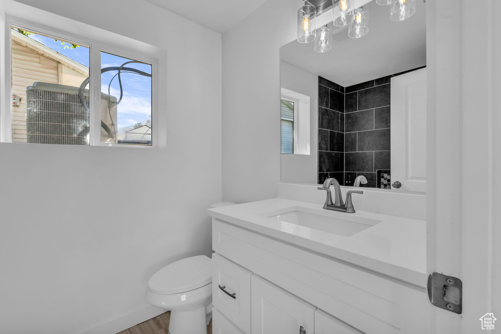 Full bathroom featuring vanity, plenty of natural light, tiled shower, and wood finished floors
