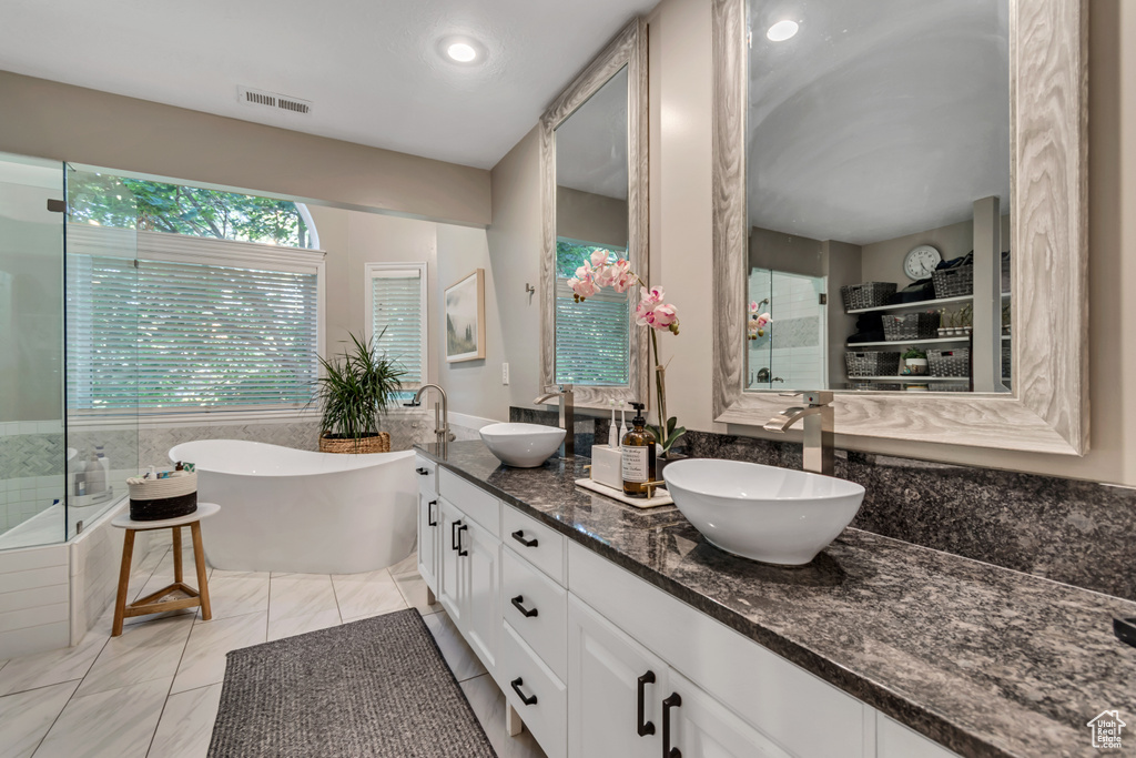 Full bathroom featuring a soaking tub, double vanity, and a shower stall