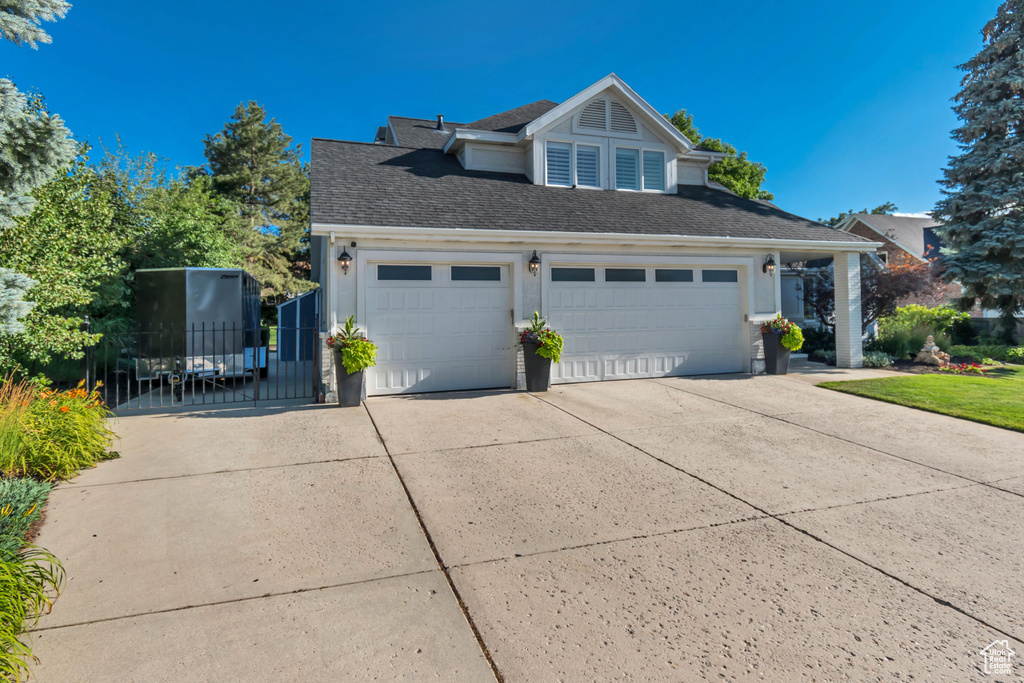 View of front facade with driveway, a shingled roof, and a garage