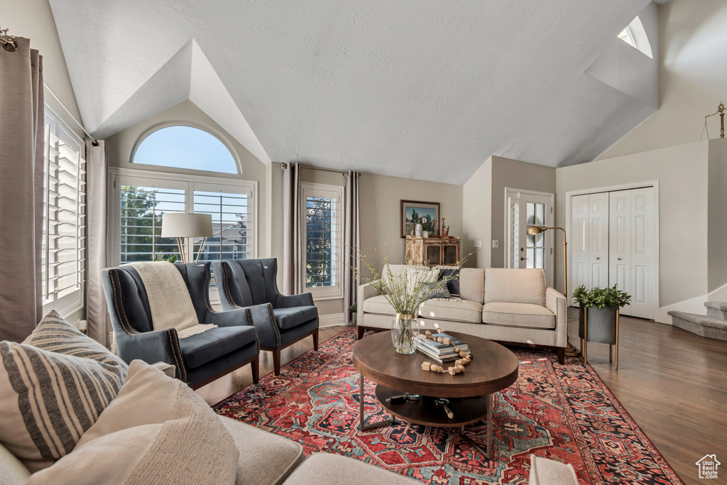 Living room featuring vaulted ceiling, wood finished floors, and stairway