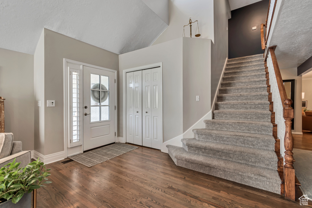 Entryway with wood finished floors, stairs, and lofted ceiling