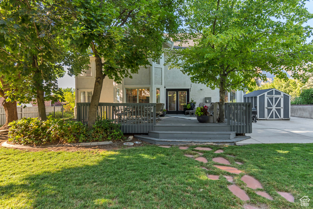 View of front of home featuring a storage shed, stucco siding, a deck, and french doors