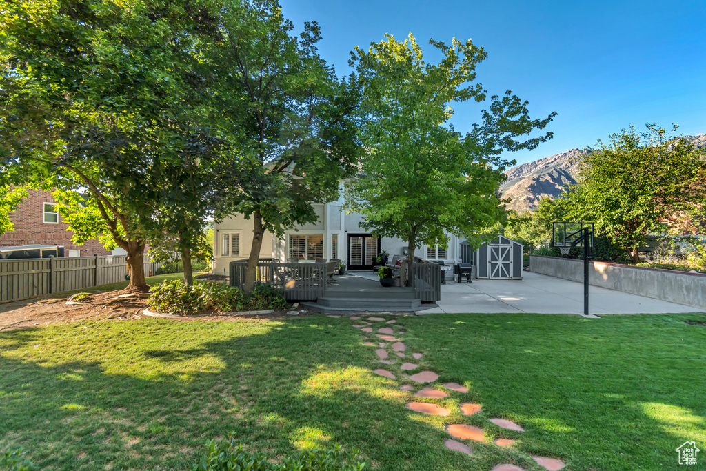 View of yard with a storage shed and a deck with mountain view