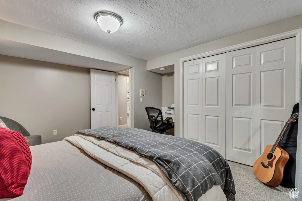 Bedroom featuring carpet floors, a closet, and a textured ceiling