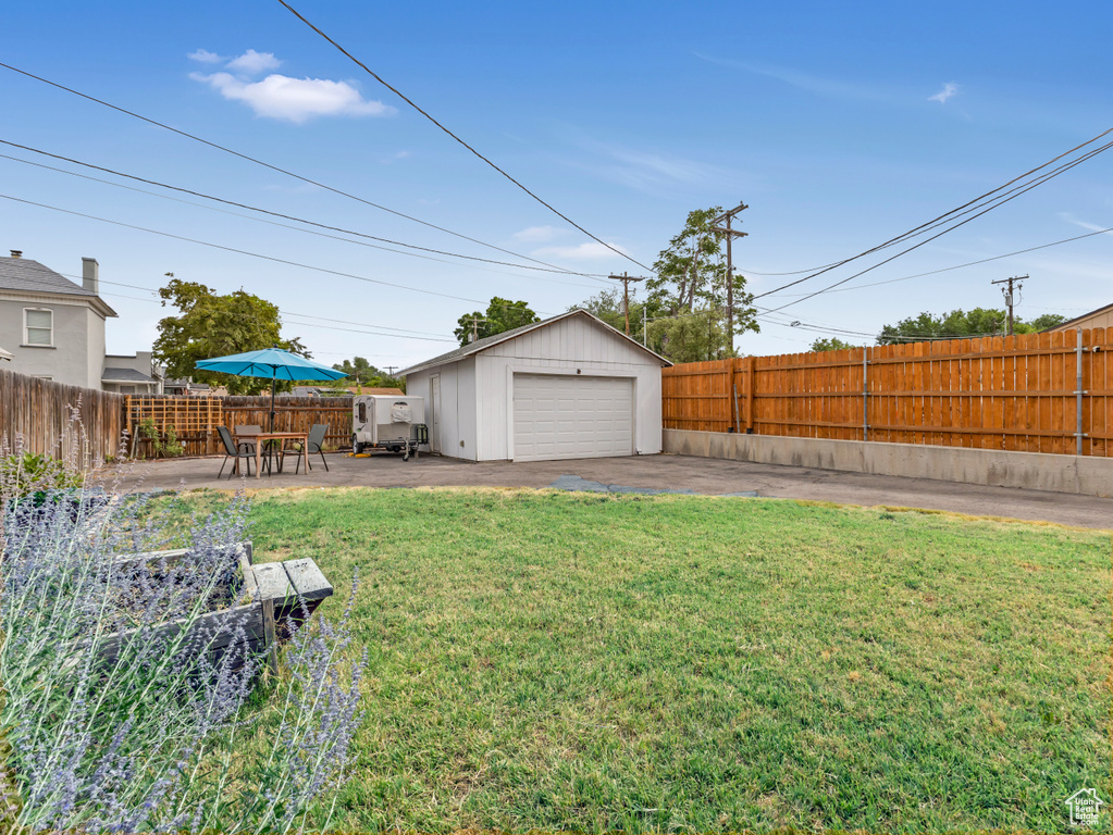Fenced backyard with a detached garage and an outbuilding