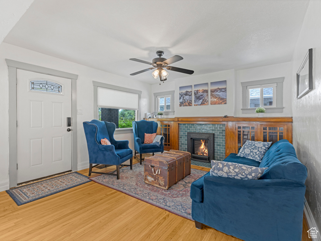 Living room featuring wood finished floors, a fireplace, and a ceiling fan