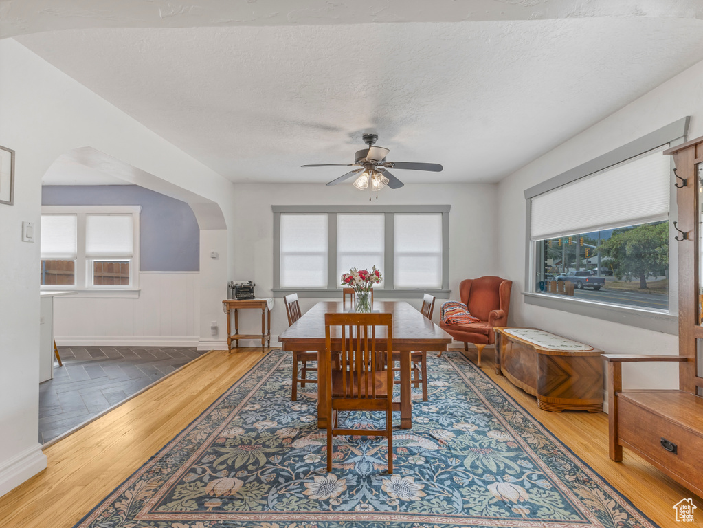 Dining area with ceiling fan, arched walkways, and wood finished floors