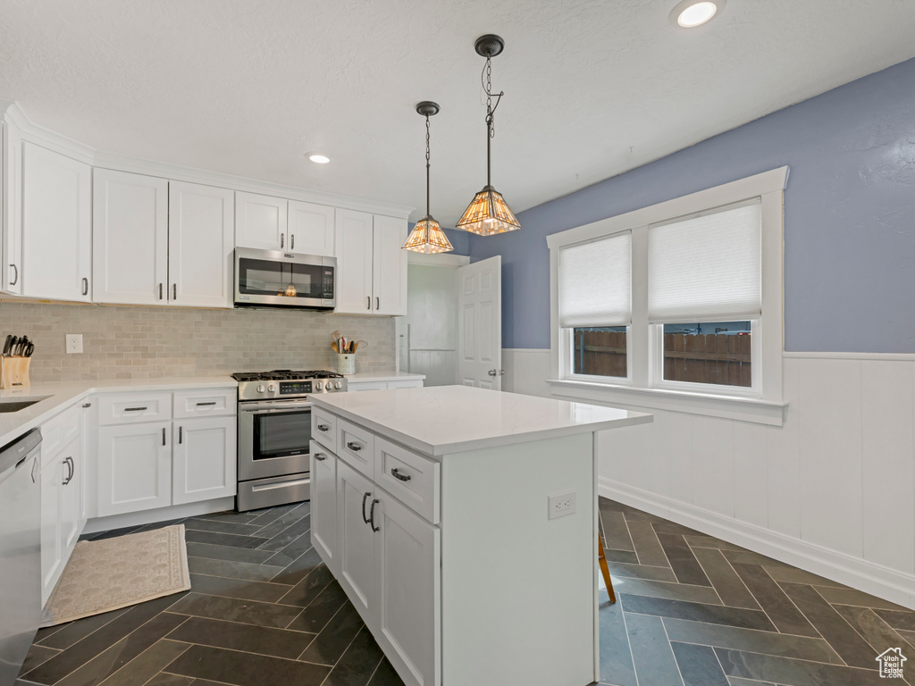 Kitchen featuring appliances with stainless steel finishes, white cabinets, light countertops, recessed lighting, and a wainscoted wall